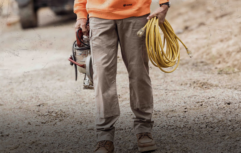 man in pants with coil of electrical cord and tools