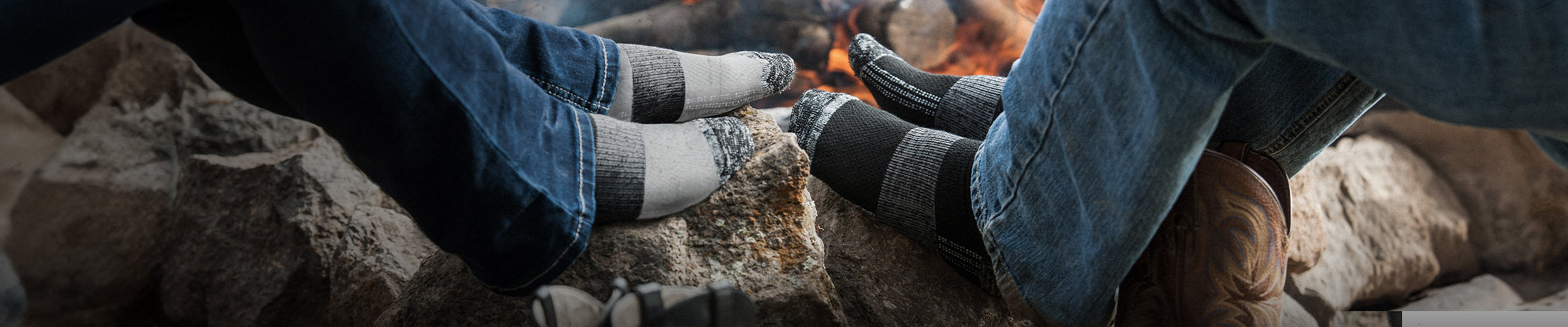 two people without shoes on warming their socks in front of a fire