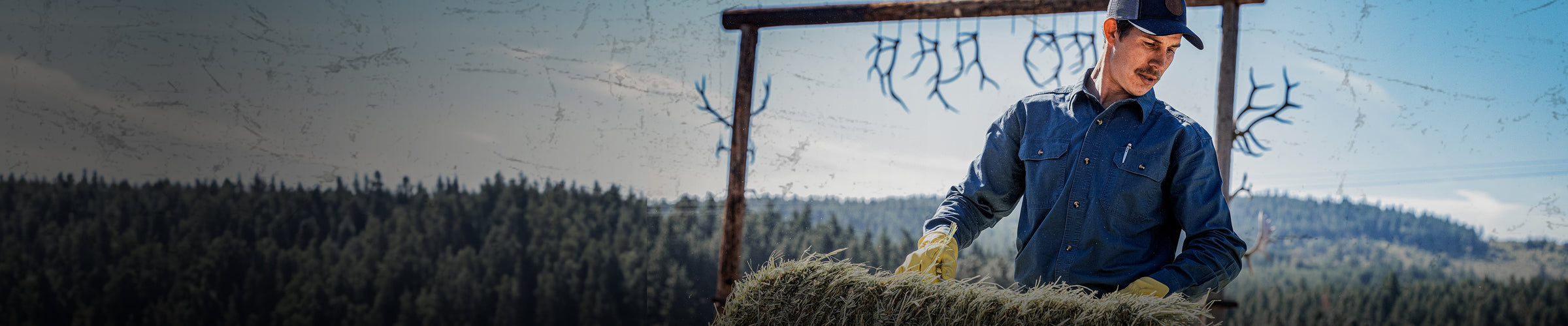 man wearing long sleeve shirt and gloves moving a bail of hay