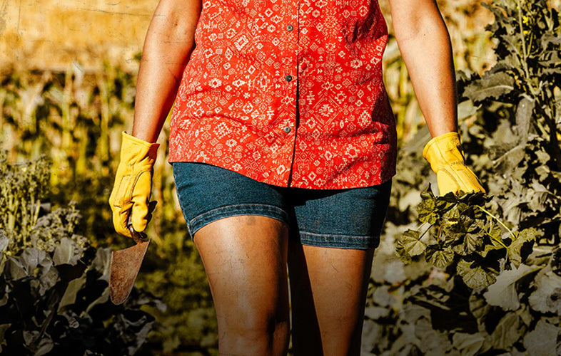 woman wearing sleeveless top and shorts working in the garden