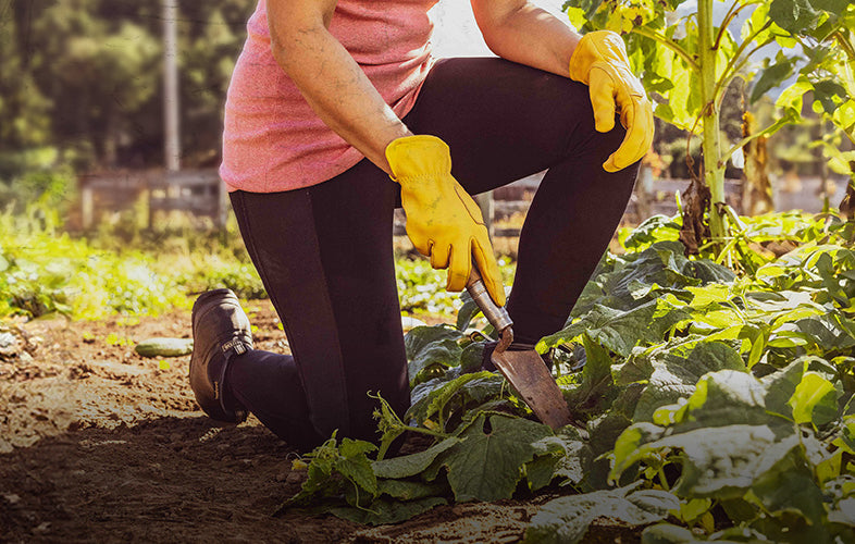 woman wearing sleeveless top and leggings kneeling down working in the garden