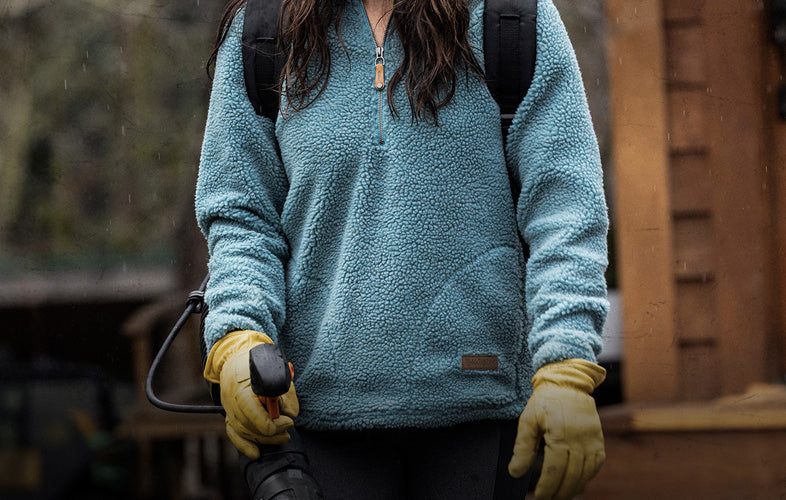 woman wearing sweatshirt using a backpack blower