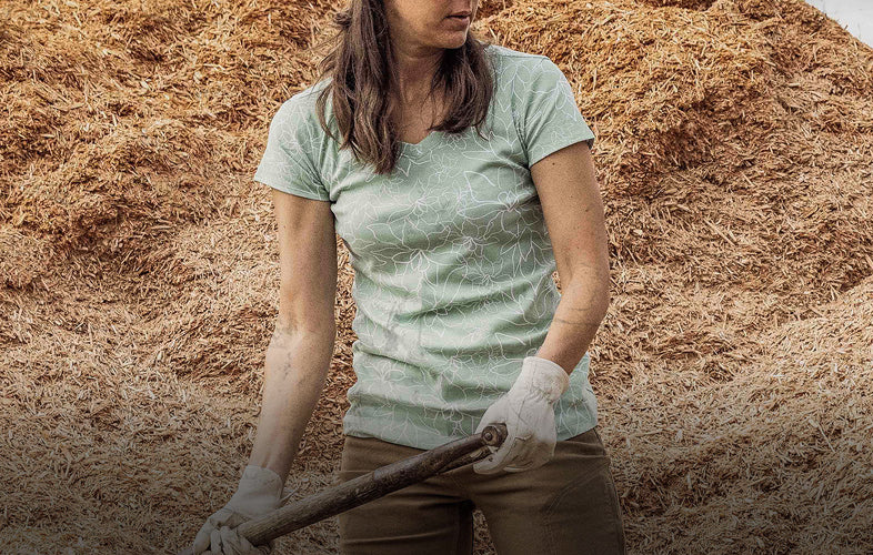 woman with t-shirt on standing in front of wood chip pile