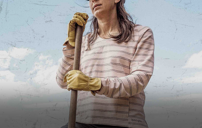 woman with gloves on holding a wooden tool